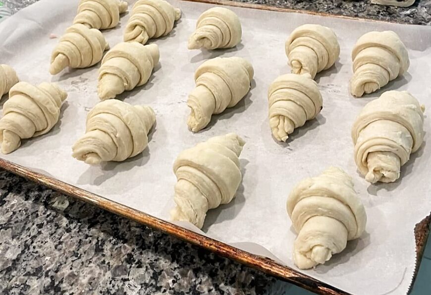 Croissants being shaped by hand on the kitchen counter