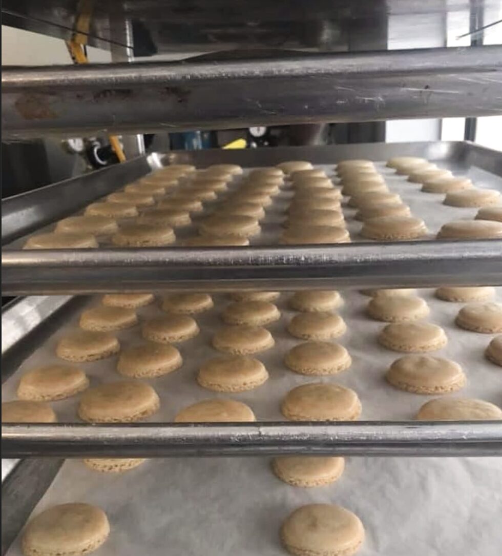 Racks of freshly baked macaron shells resting on parchment